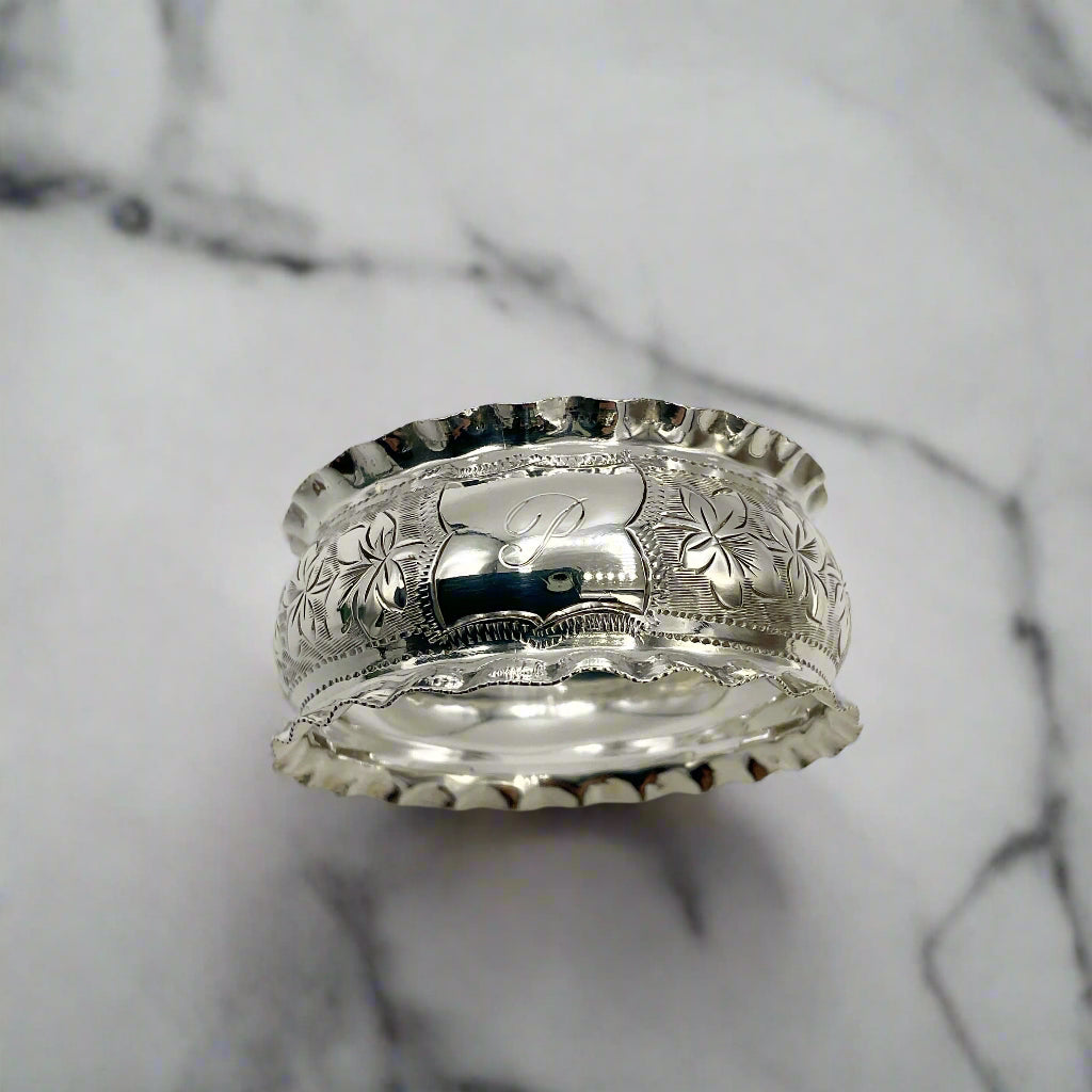 Silver napkin ring with intricate designs on a marble surface