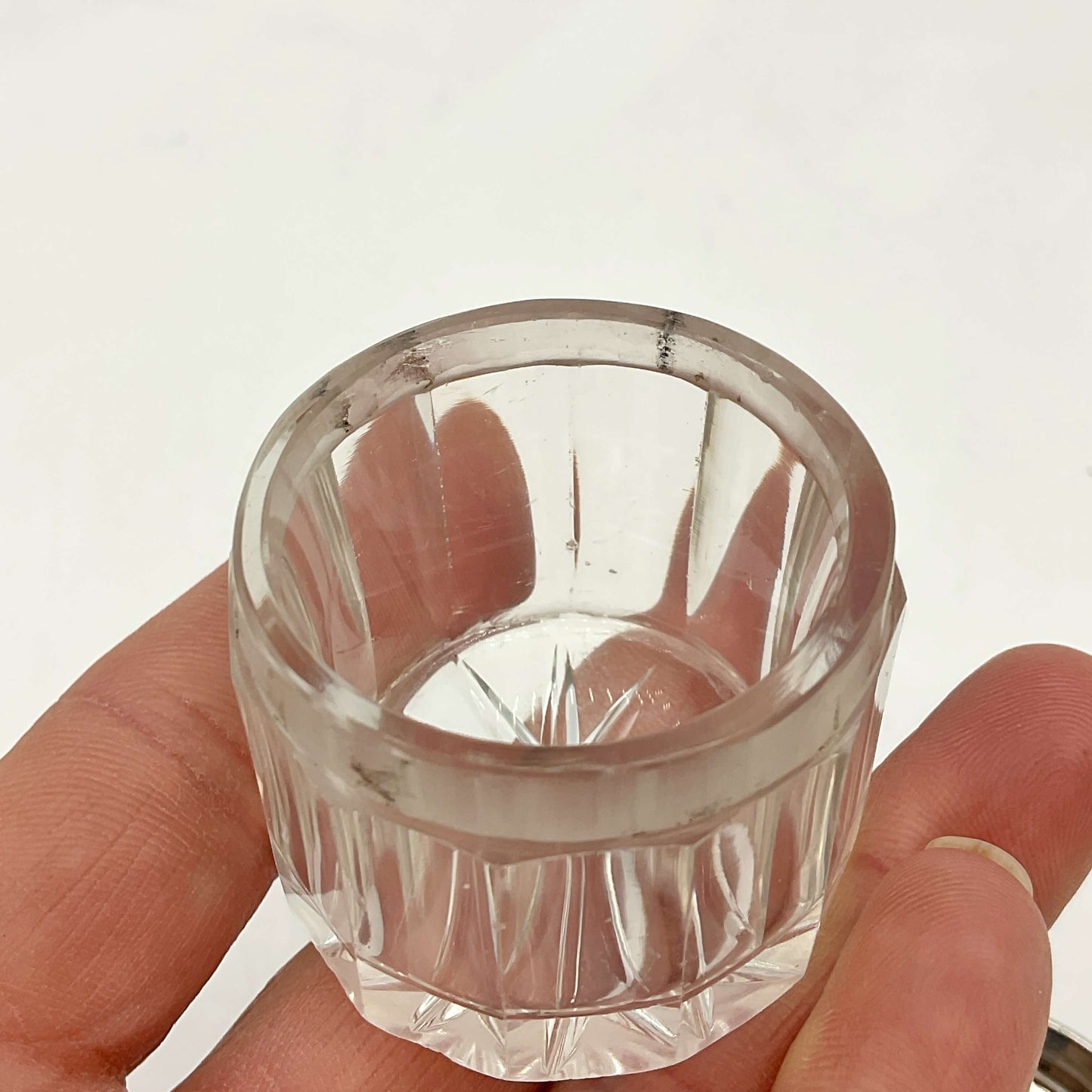 Clear glass jar held between fingers against a white background