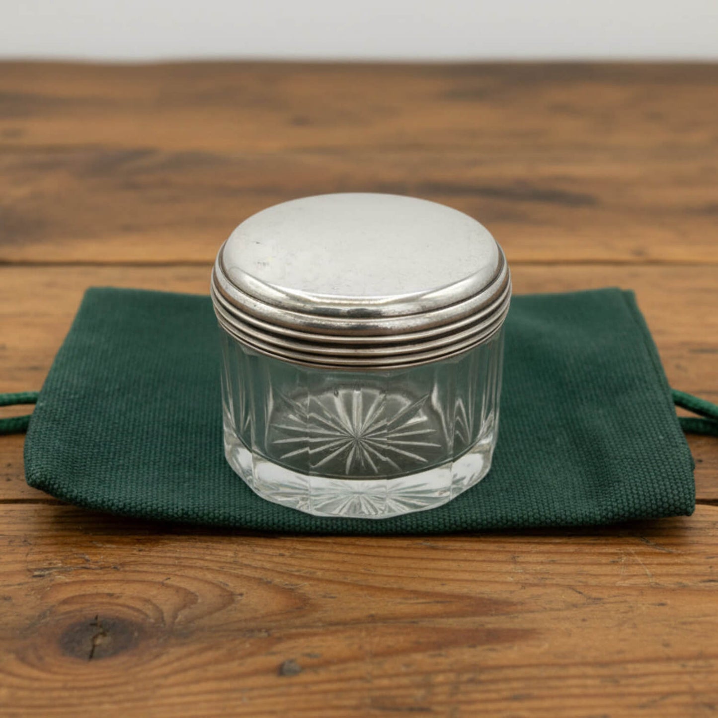 Glass jar with silver lid on a green cloth over a wooden surface