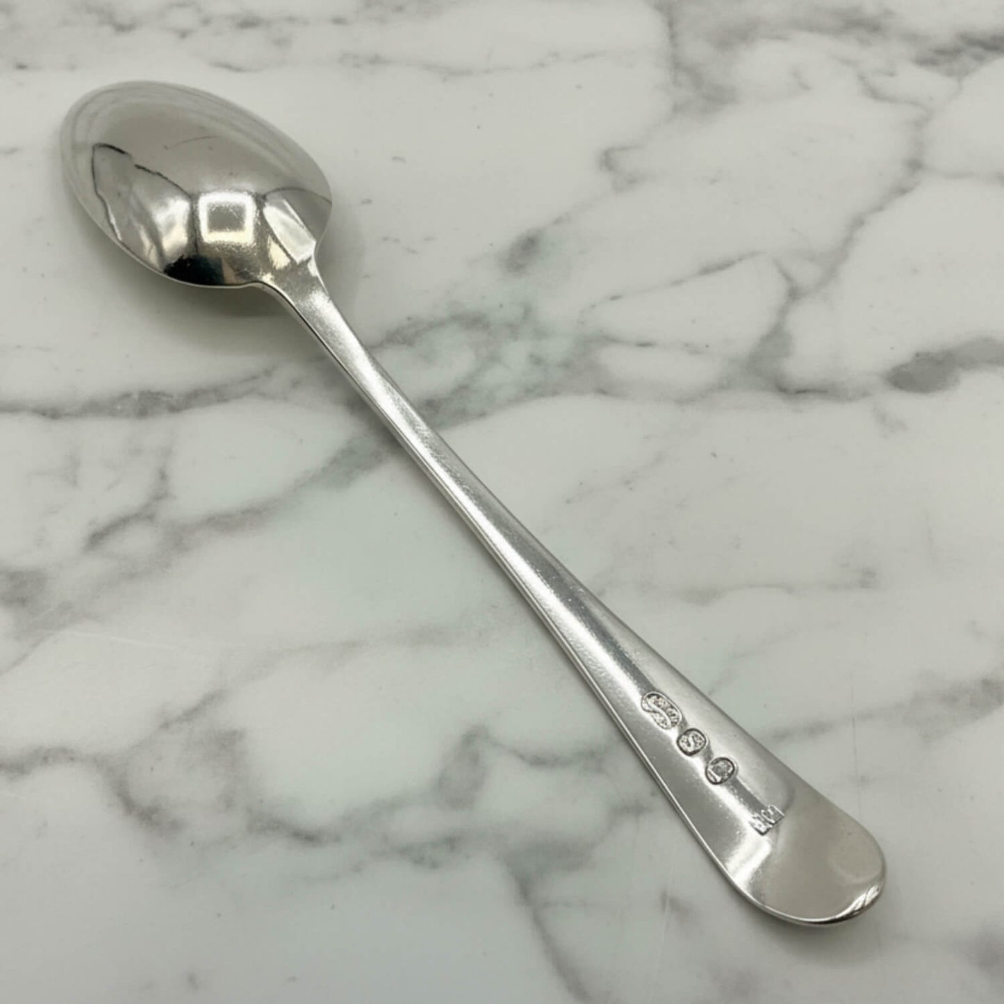 back of a Silver spoon on a marble surface