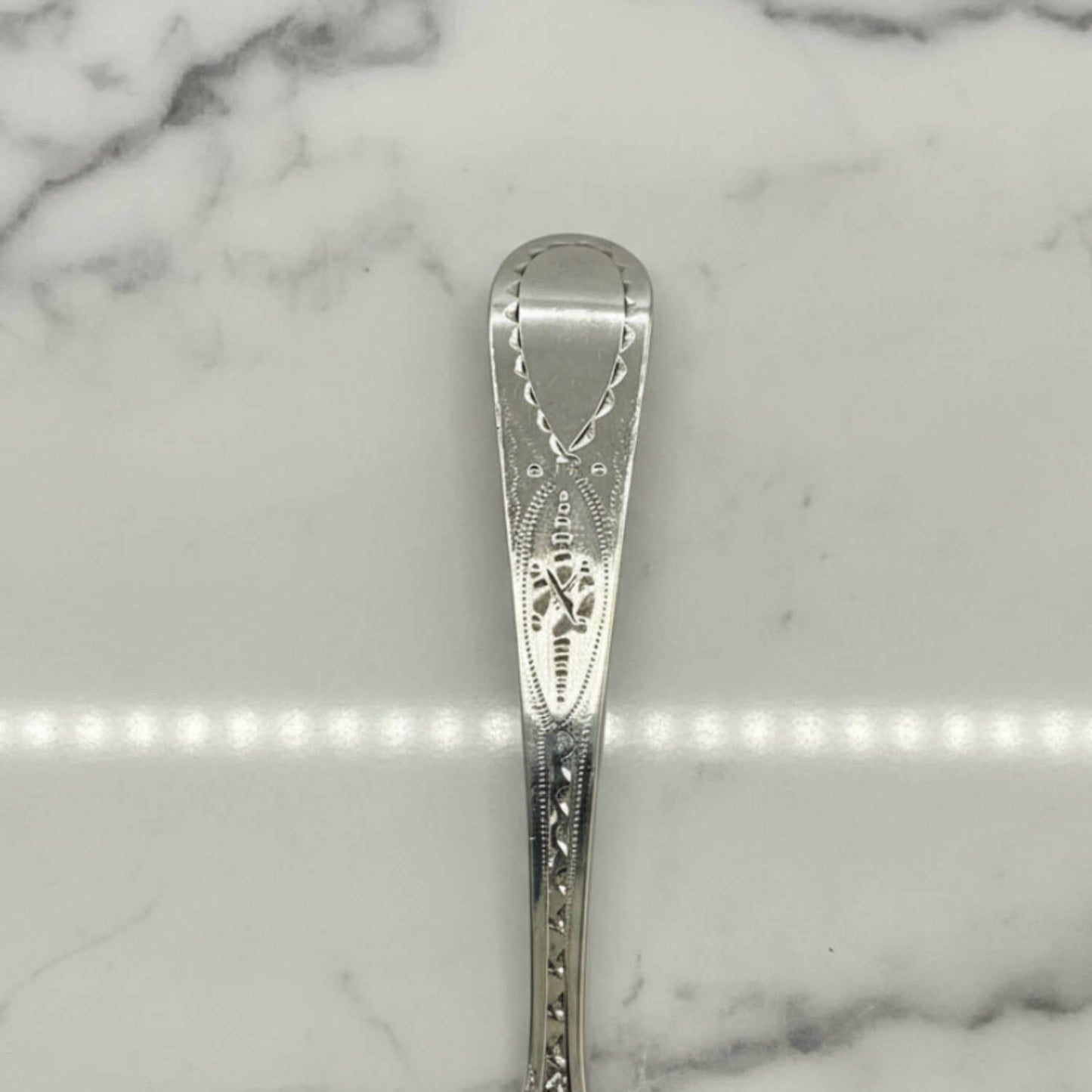 Silver spoon with intricate design on a marble surface