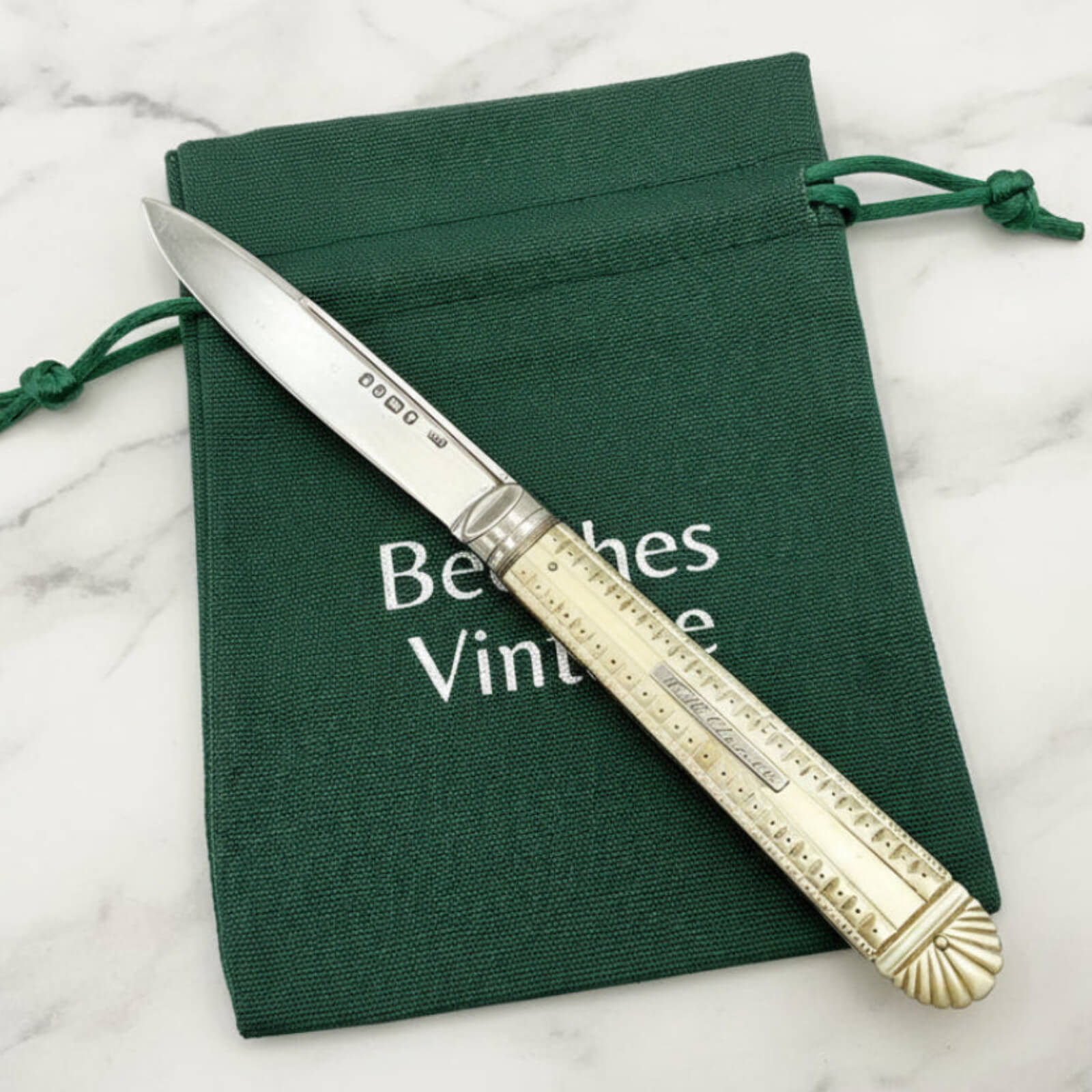 Decorative knife with gold handle on a green cloth with 'Beeches Vintage' text