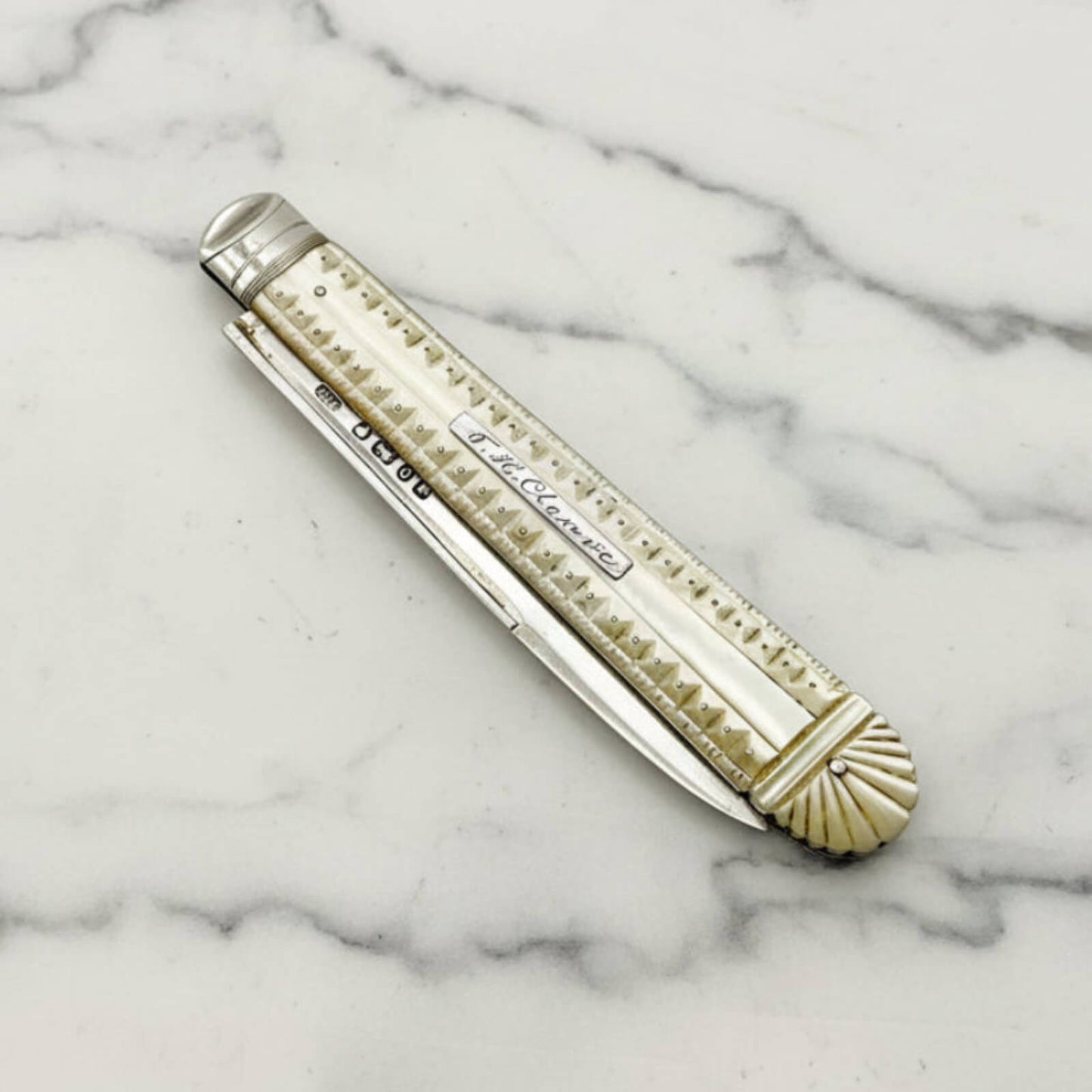 Silver and pearl pocket knife on a marble surface