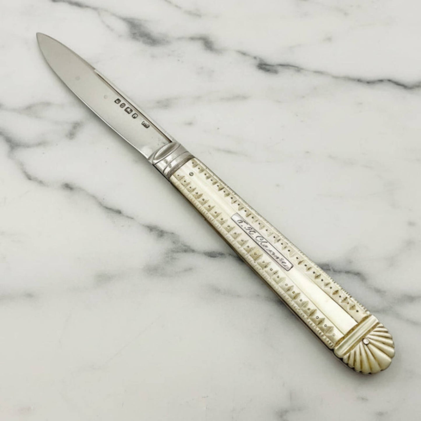 Decorative knife with a mother of pearl handle on a marble surface