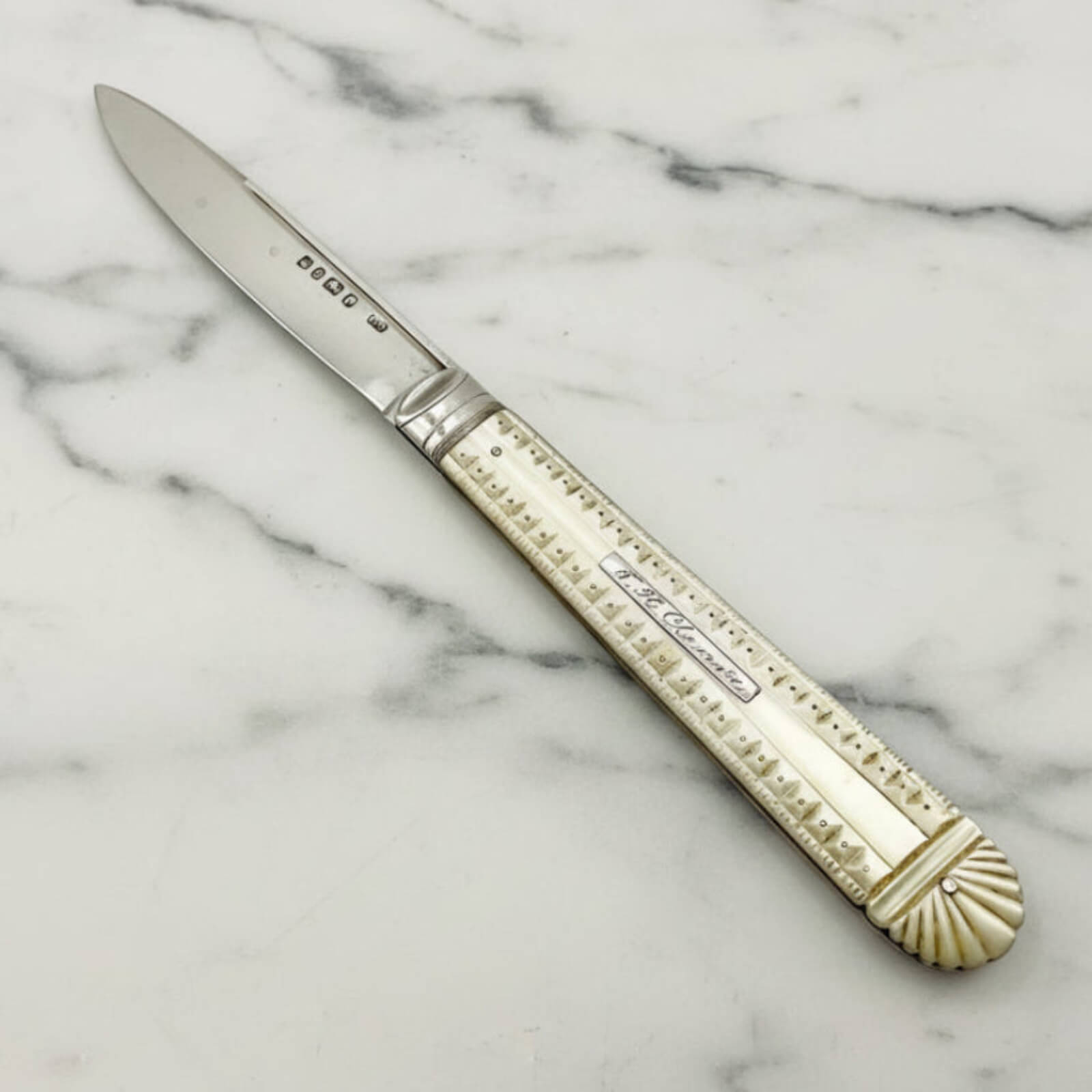 Decorative knife with a mother of pearl handle on a marble surface