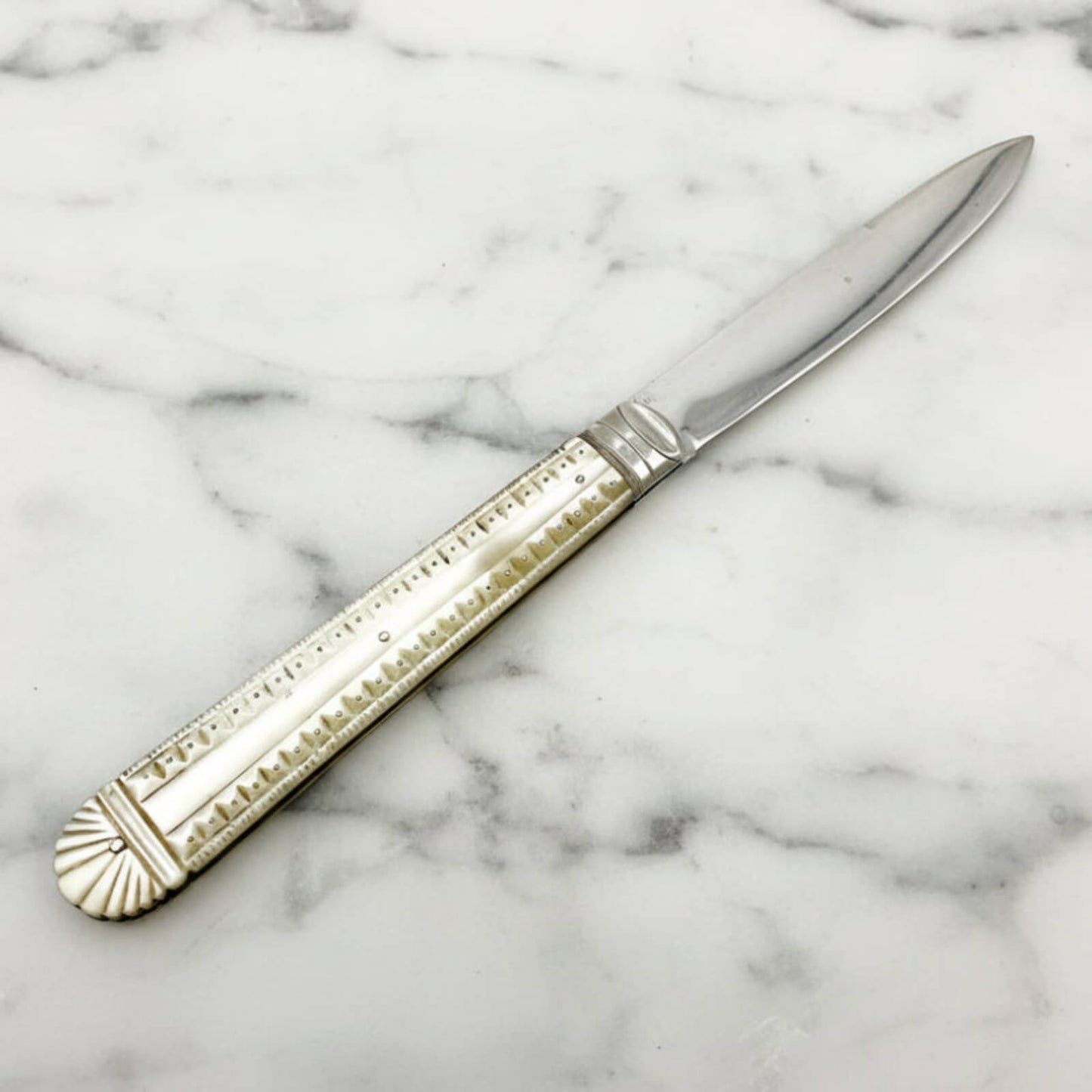 Decorative knife with a pearl handle on a marble surface
