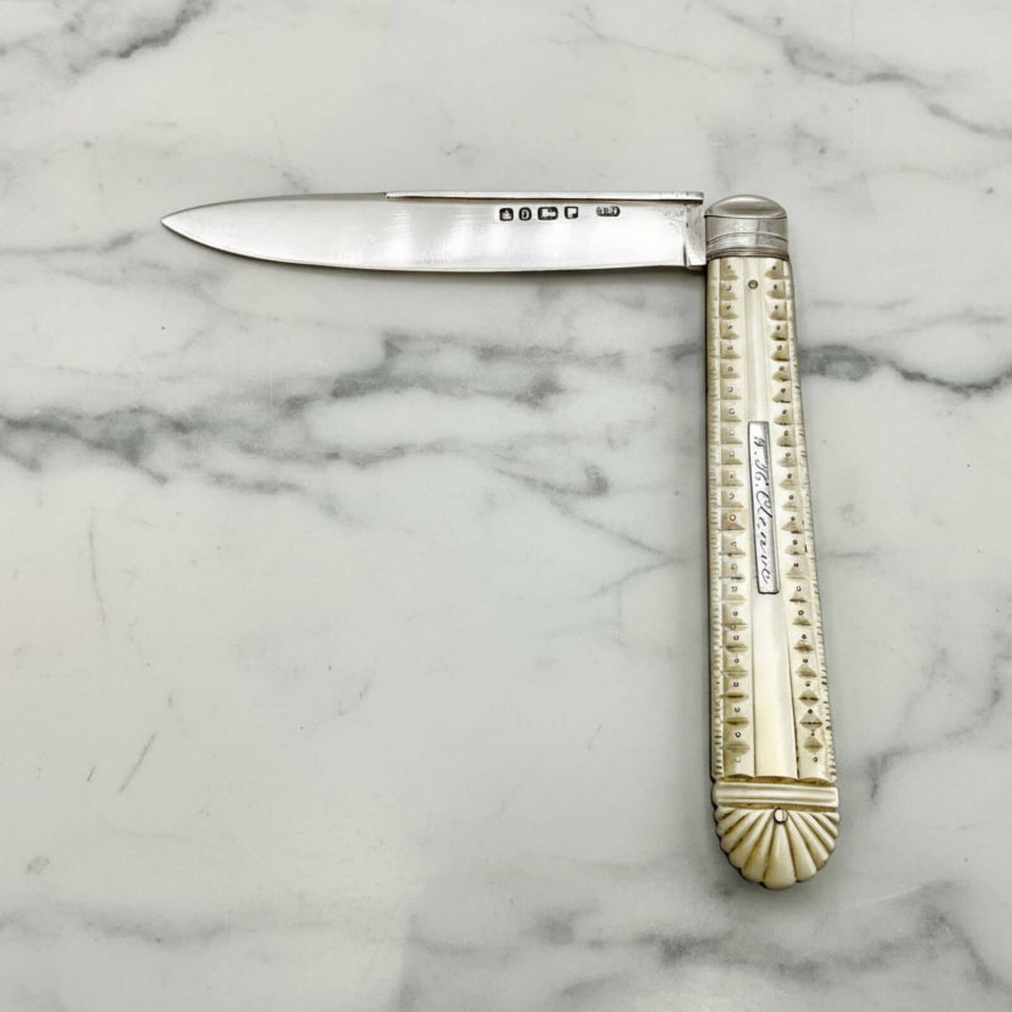 Antique folding knife with decorative handle on a marble surface