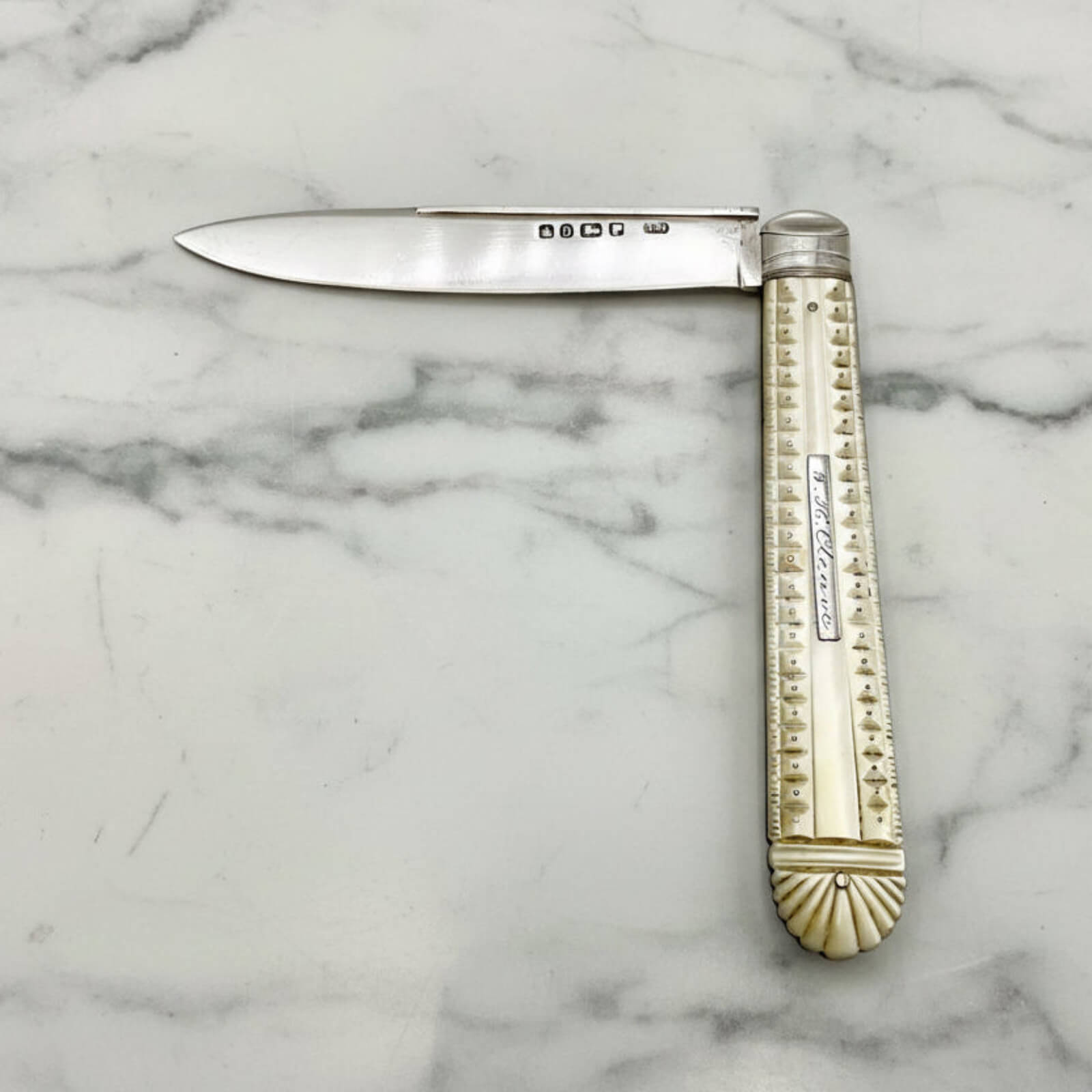 Antique folding knife with decorative handle on a marble surface