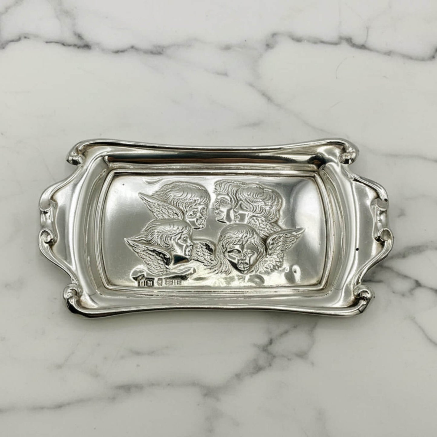 Silver tray with engraved designs on a marble surface