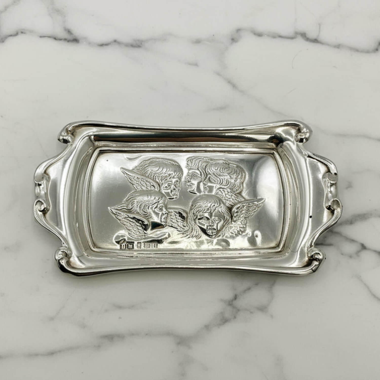 Silver tray with engraved designs on a marble surface