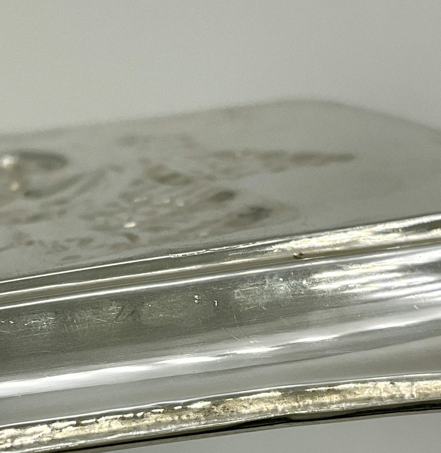 Close-up of a silver tray base with engraved details on a white background