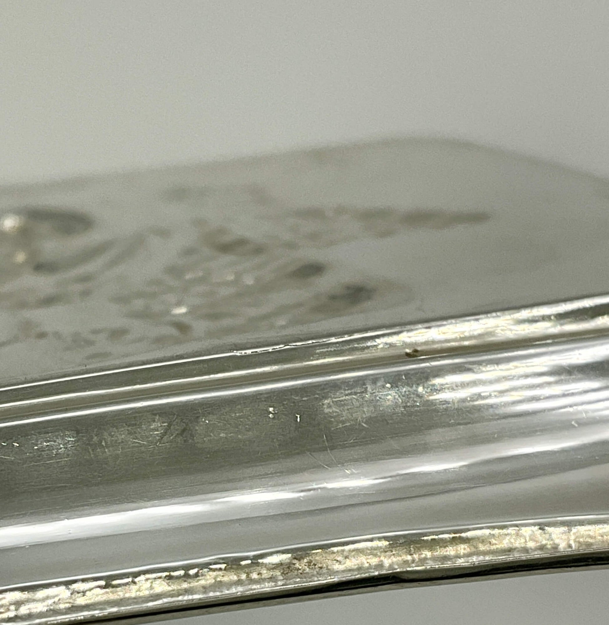 Close-up of a silver tray base with engraved details on a white background