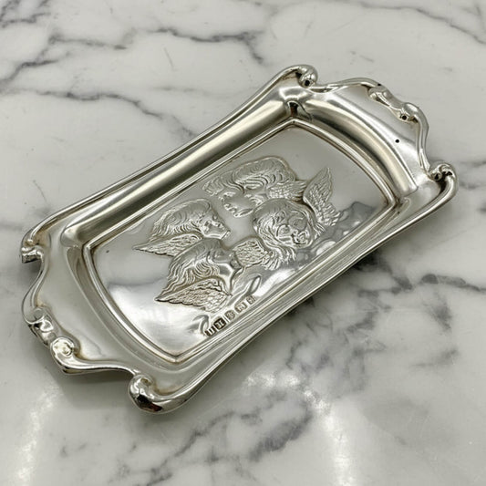 Silver tray with cherub design on a marble surface