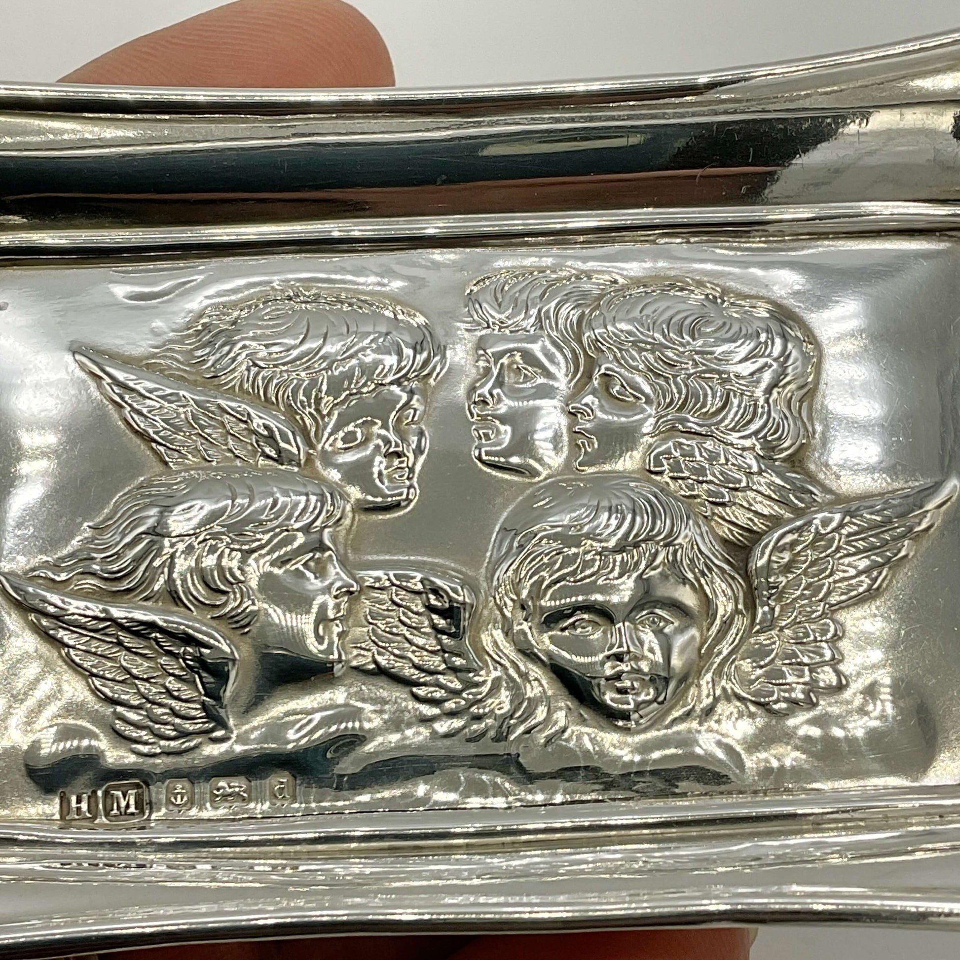 Silver tray with cherub faces and wings embossed on it