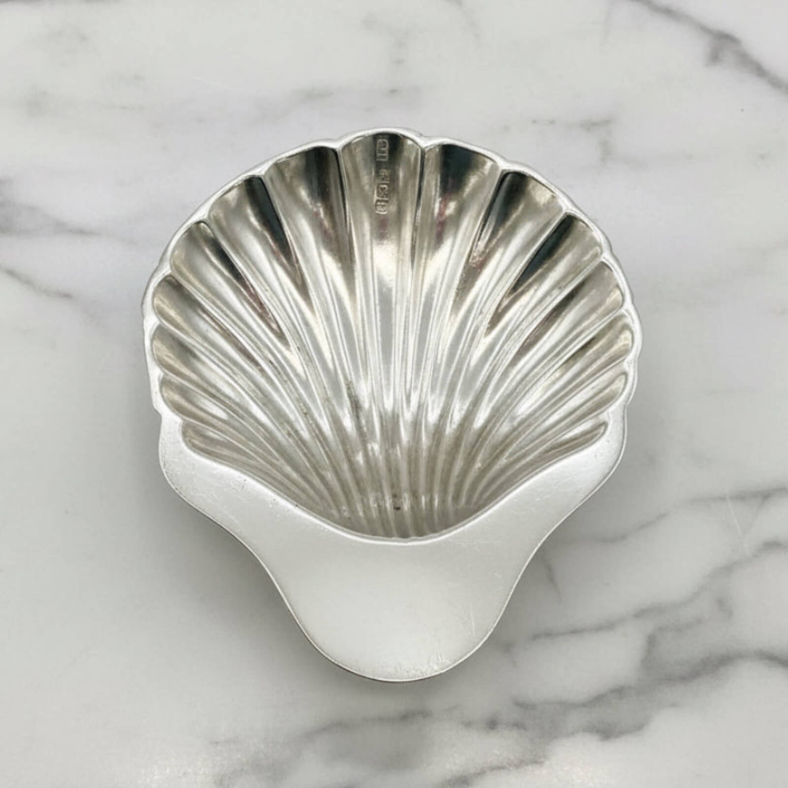 Silver shell-shaped bowl on a marble surface