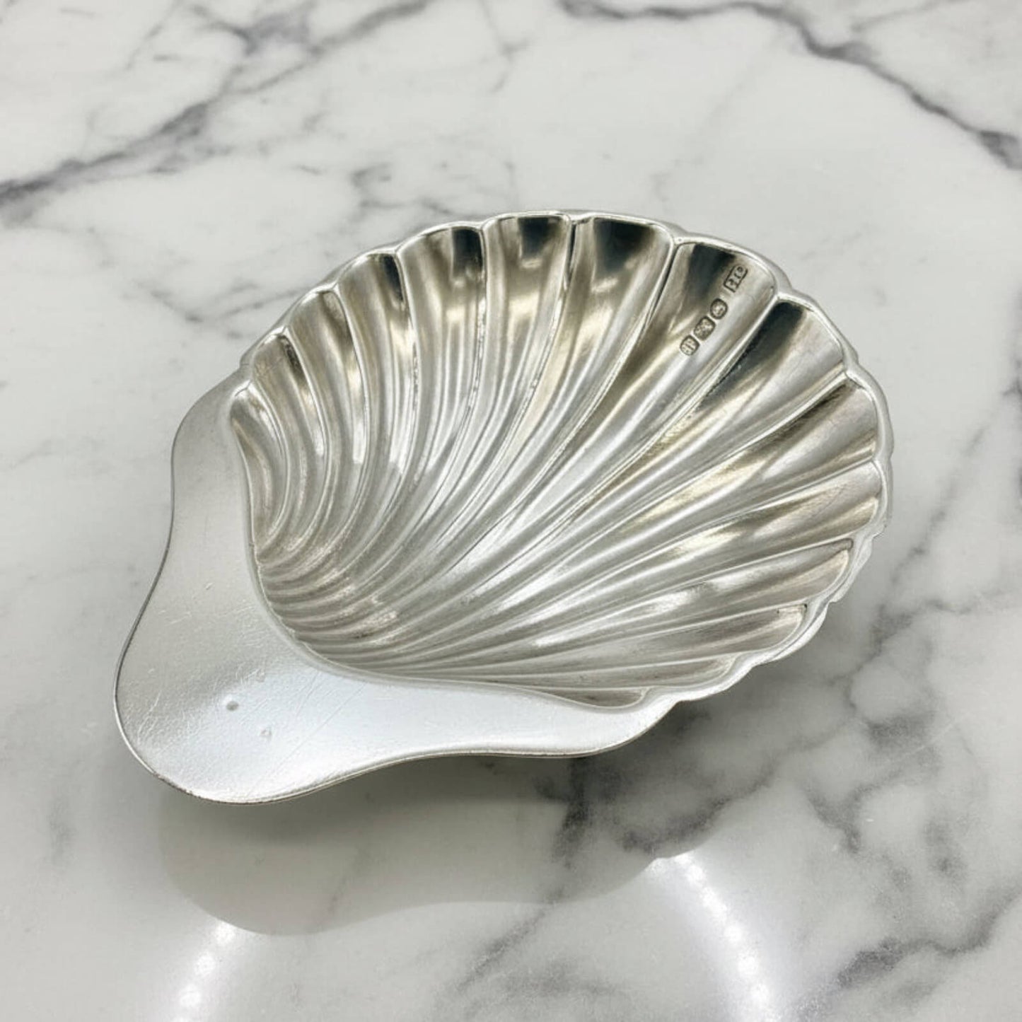 Silver shell-shaped dish on a marble surface