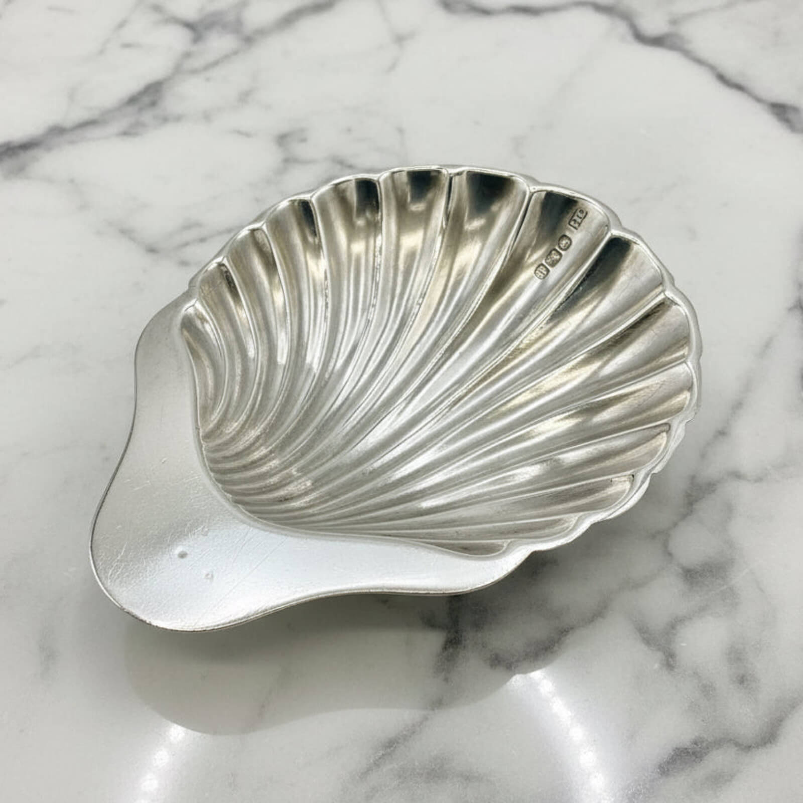 Silver shell-shaped dish on a marble surface
