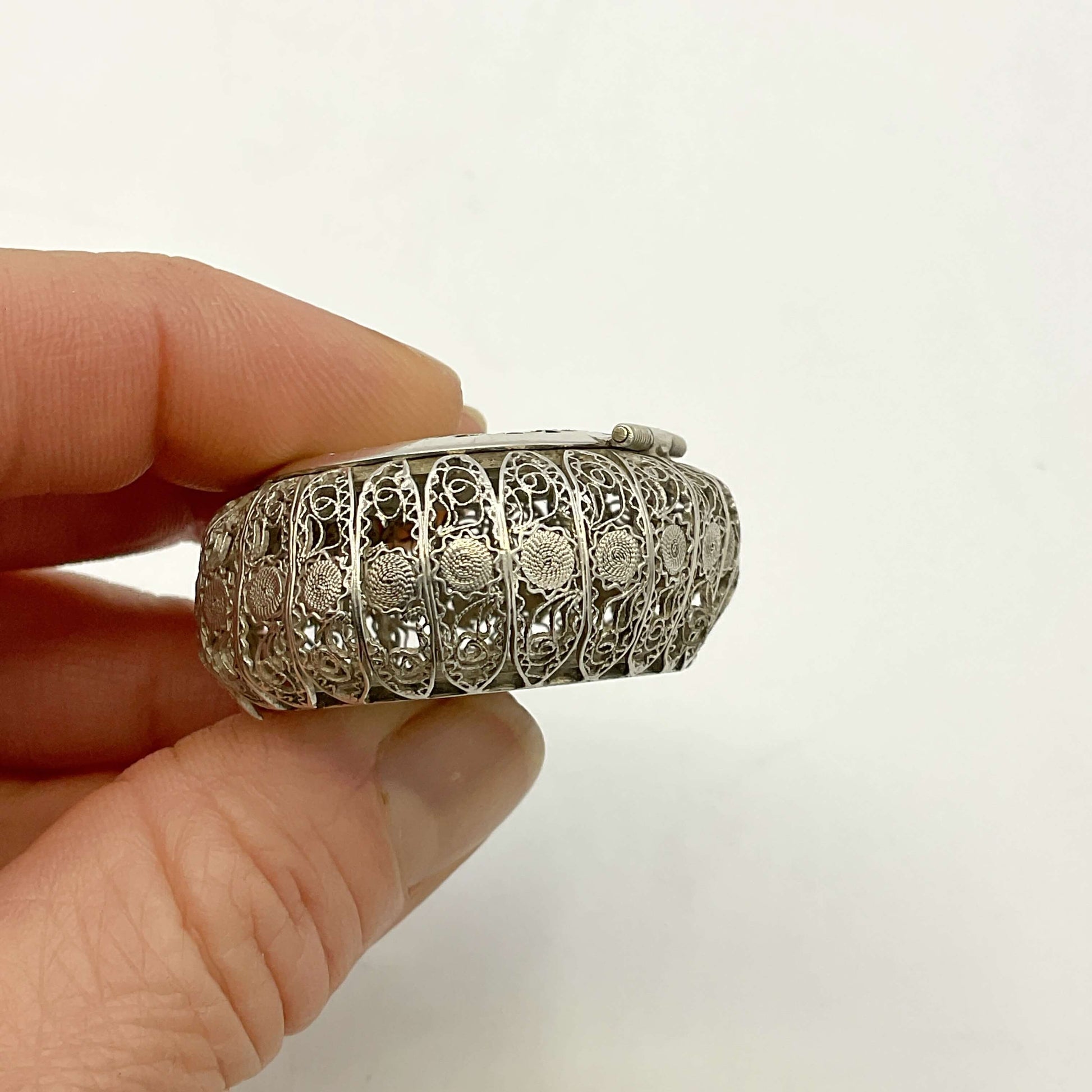 Hand holding a Antique Silver Filigree Box against a plain background