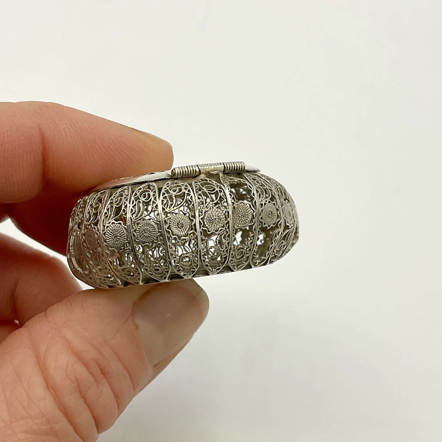 Antique Silver Filigree Box with intricate designs held by a hand against a white background