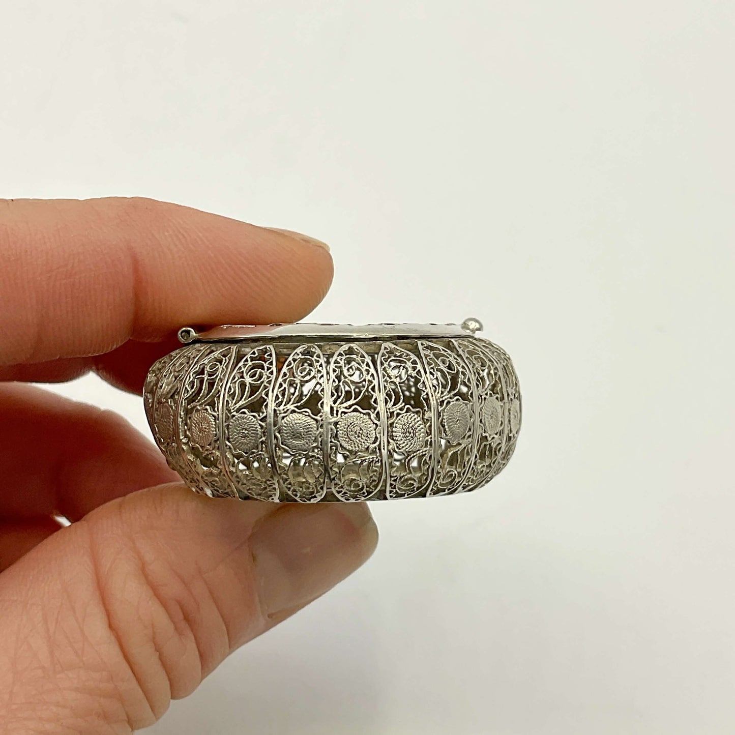 Antique Silver Filigree Box held by a hand against a plain background