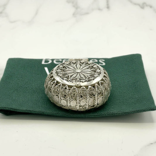 Decorative silver metal box on a green fabric with 'Beeches' text