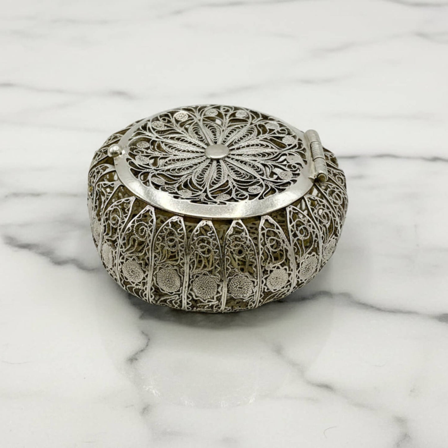 Decorative silver box with intricate patterns on a marble surface