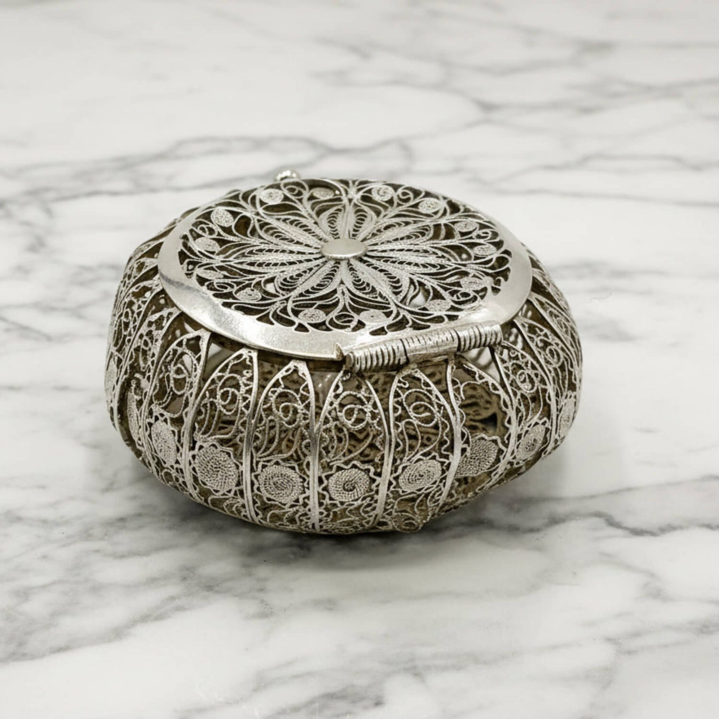 Decorative silver box with intricate patterns on a marble surface