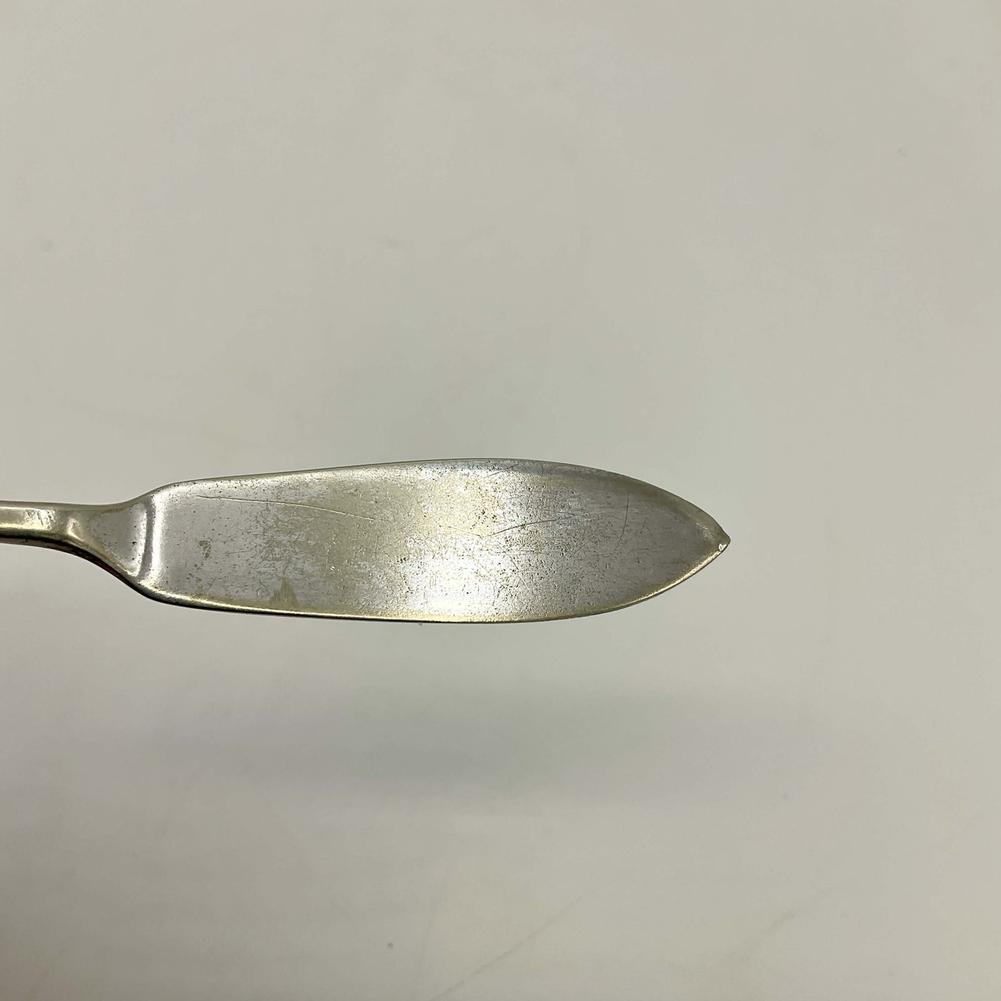 Silver plated butter knife blade on a light gray background