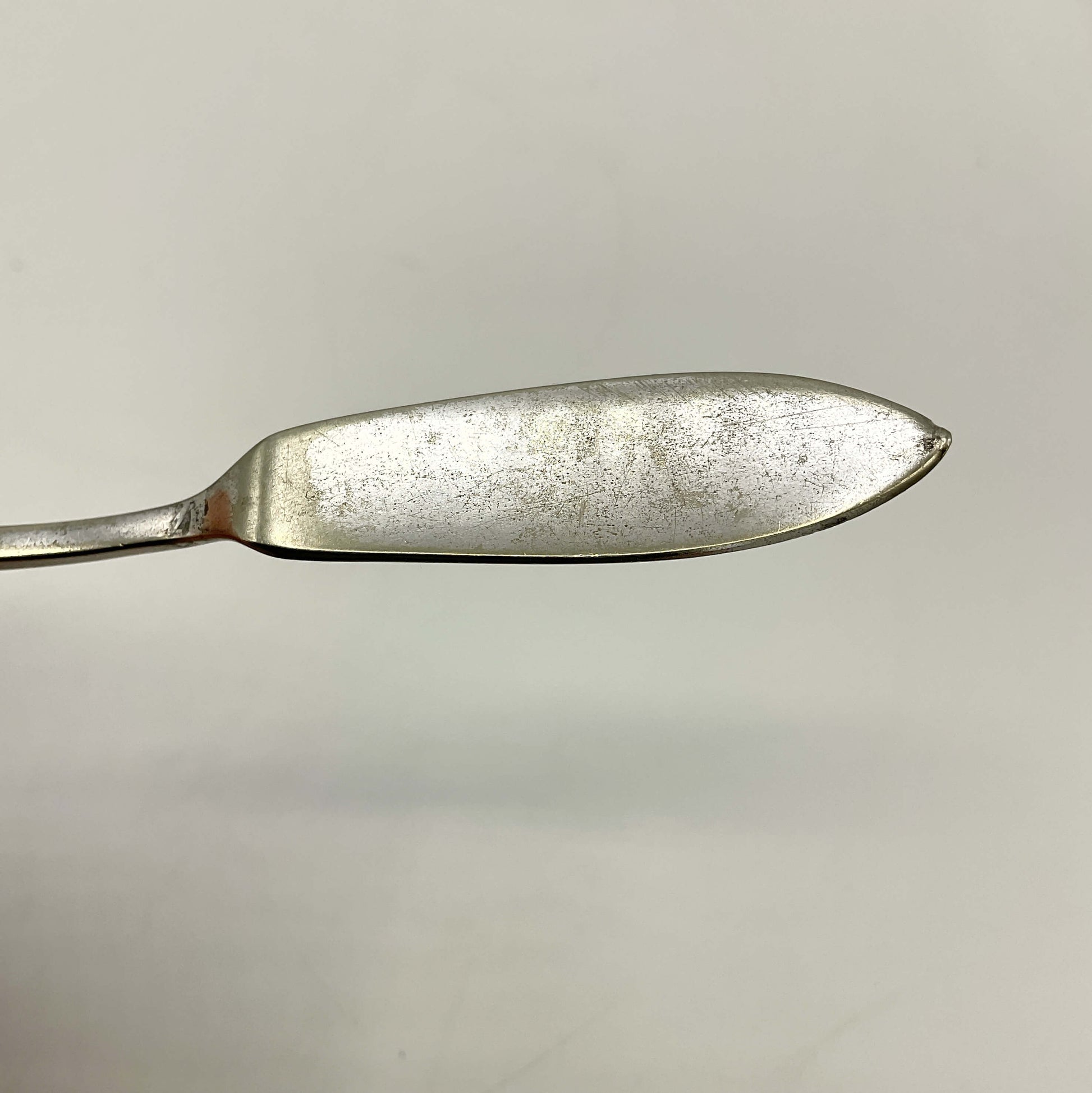 Silver plated butter knife blade on a light gray background