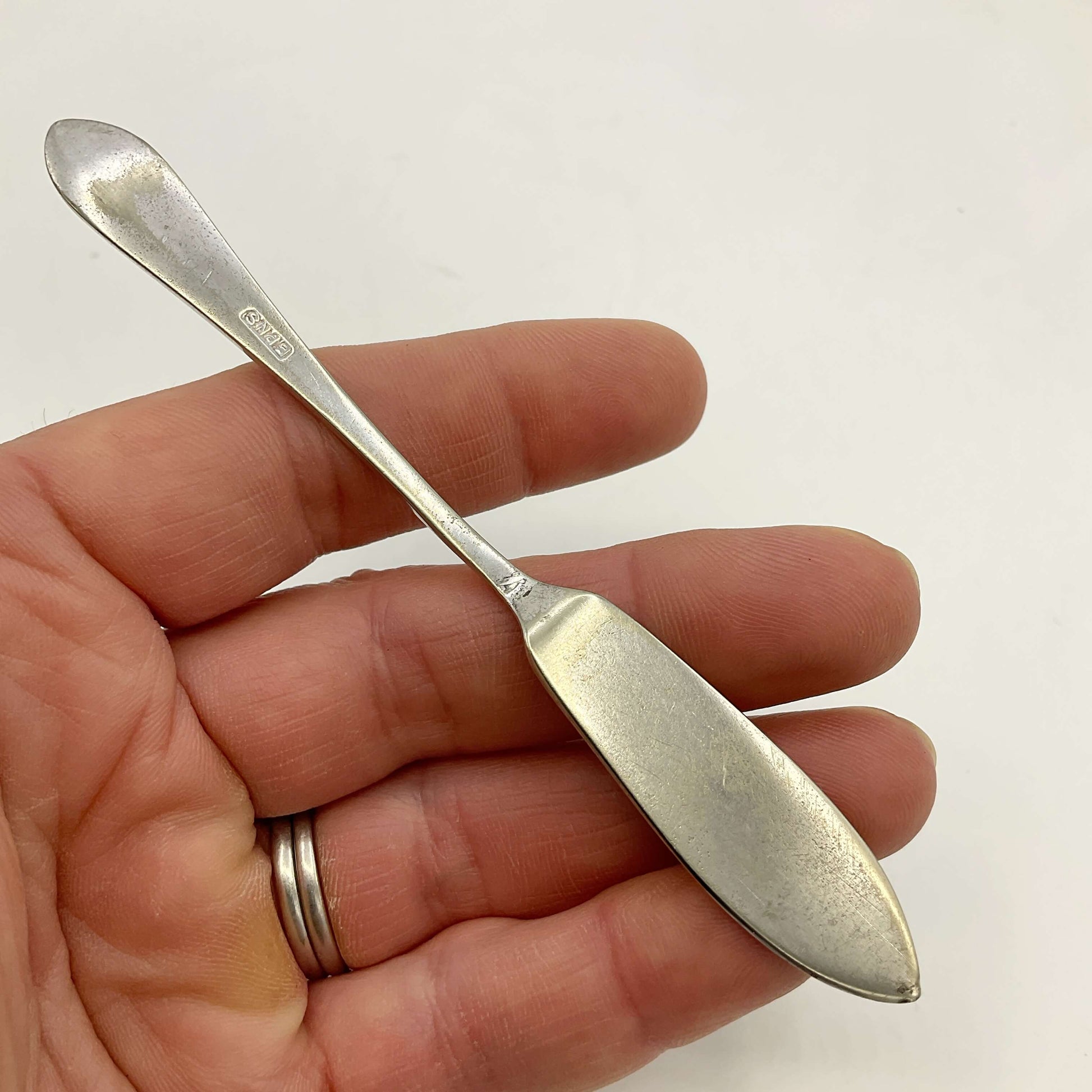 Silver plated butter knife held in a hand against a white background