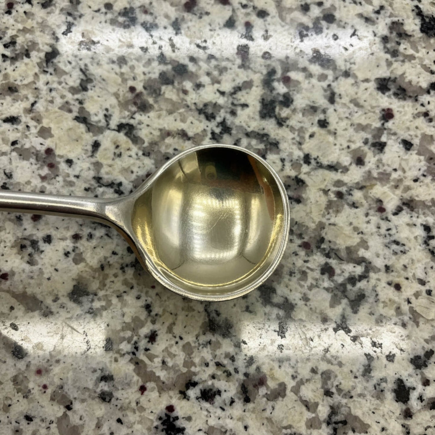 Silver spoon on a speckled granite countertop
