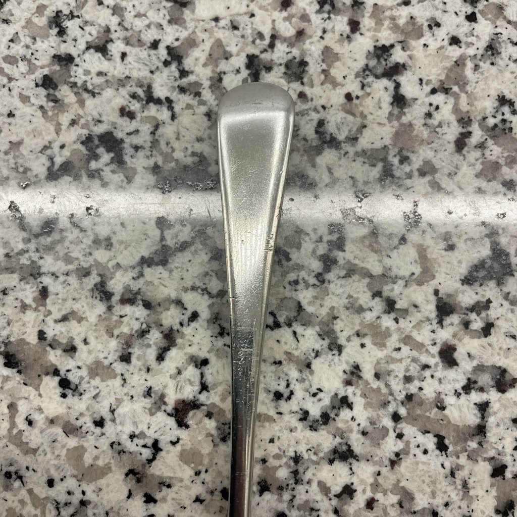 Silver spoon handle on a speckled granite countertop