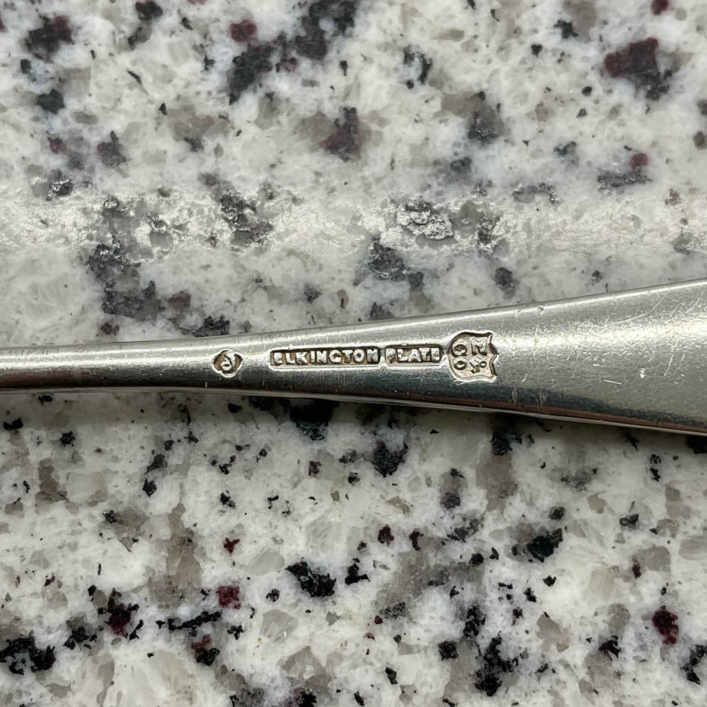 Silver spoon with 'Elkington Plate' branding on a speckled granite surface