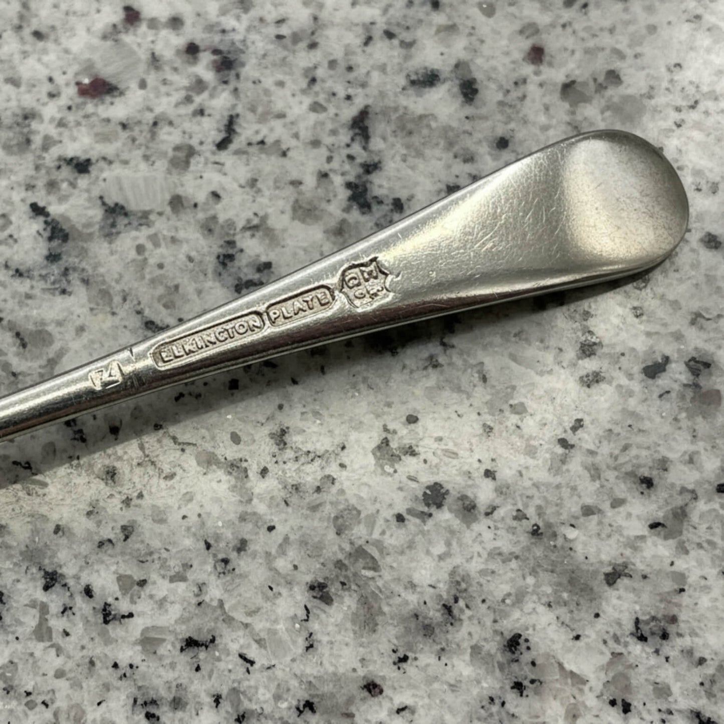 Silver spoon with 'Elkington & Co.' and Elkington Plate on a speckled grey surface