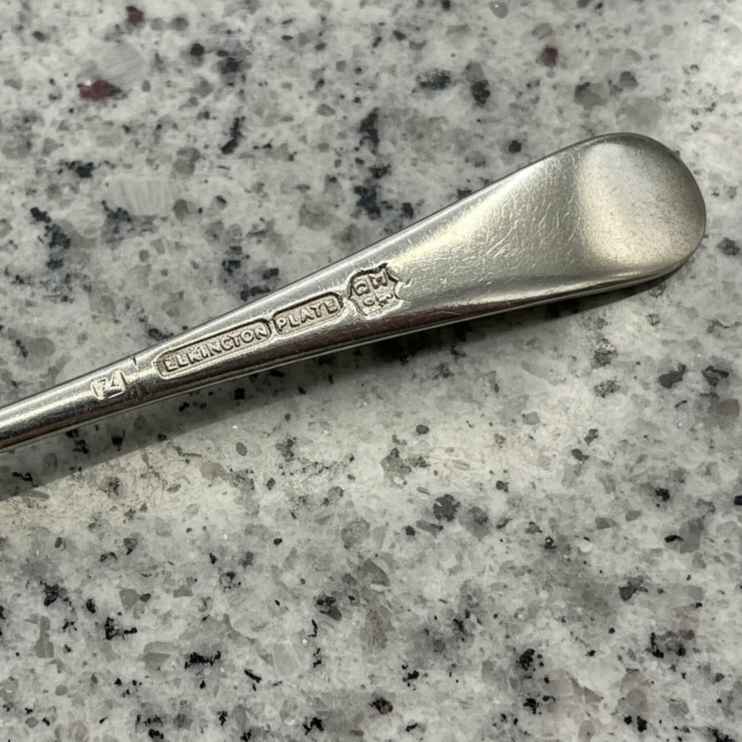 Silver spoon with 'Elkington & Co.' and Elkington Plate on a speckled grey surface
