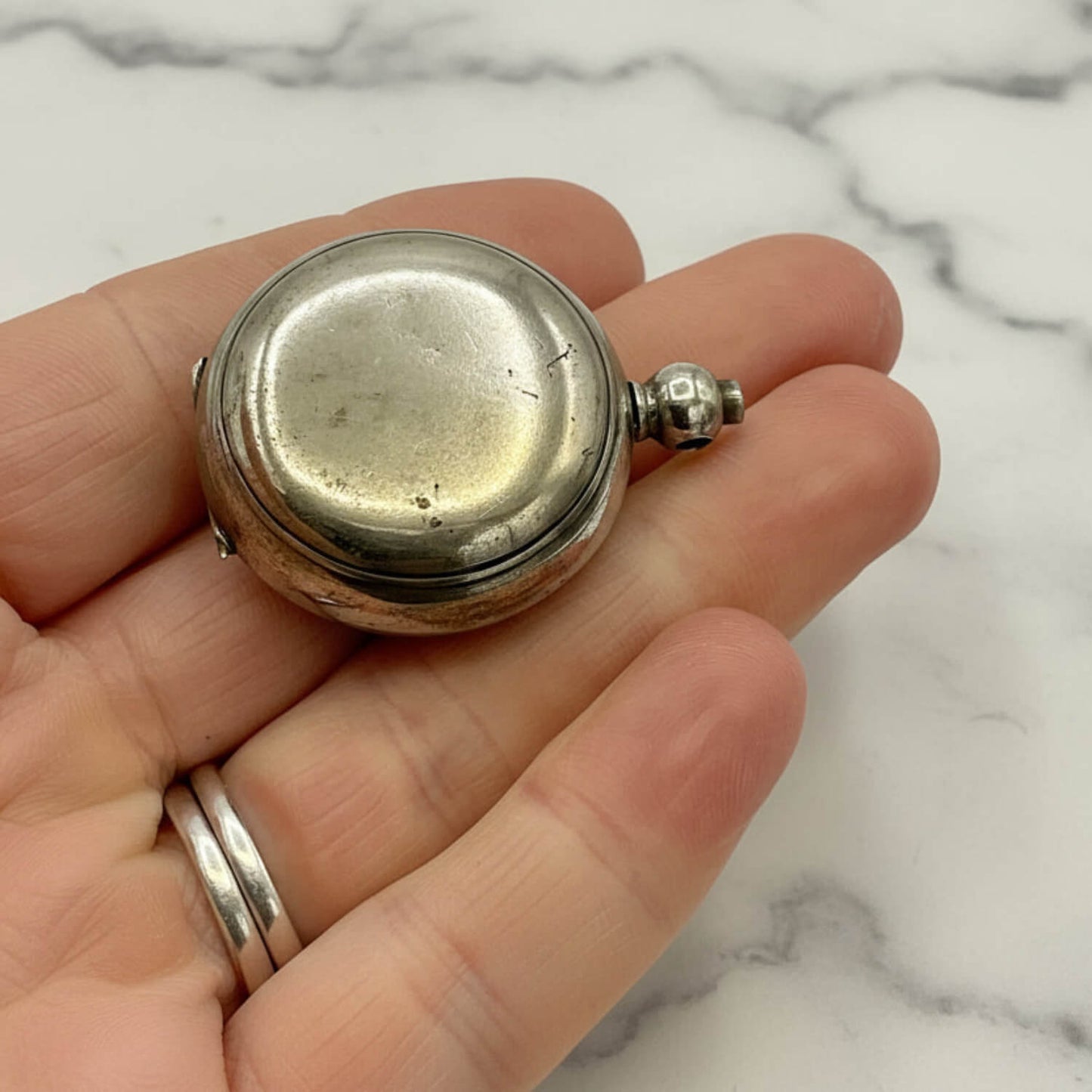 Antique Silver Plated Sovereign Case held in a hand against a marble background
