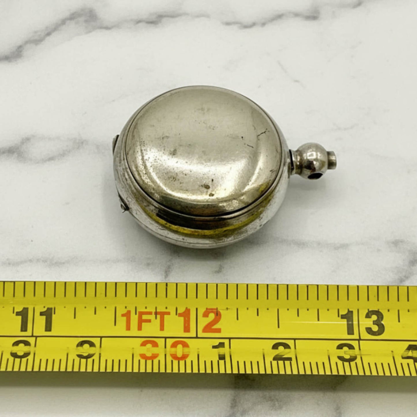 Antique Silver Plated Sovereign Case on a marble surface with a yellow measuring tape for scale.