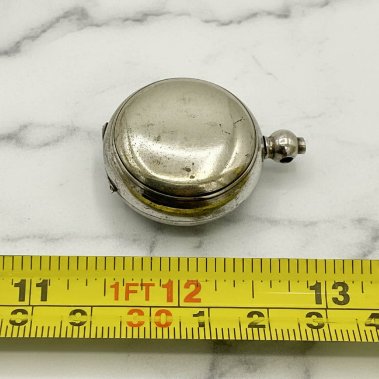 Antique Silver Plated Sovereign Case on a marble surface with a yellow measuring tape for scale.