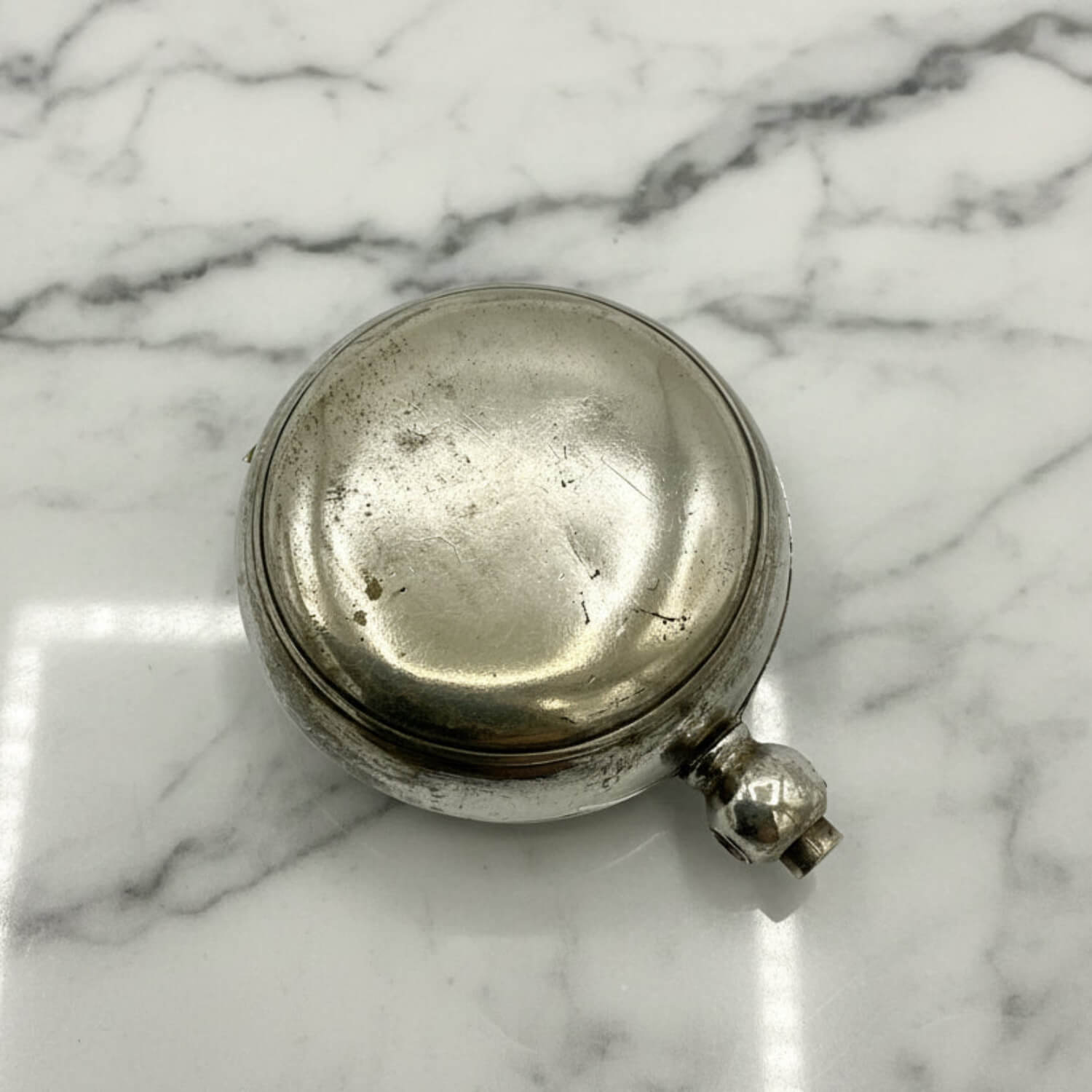Silver round sovereign case on a marble surface