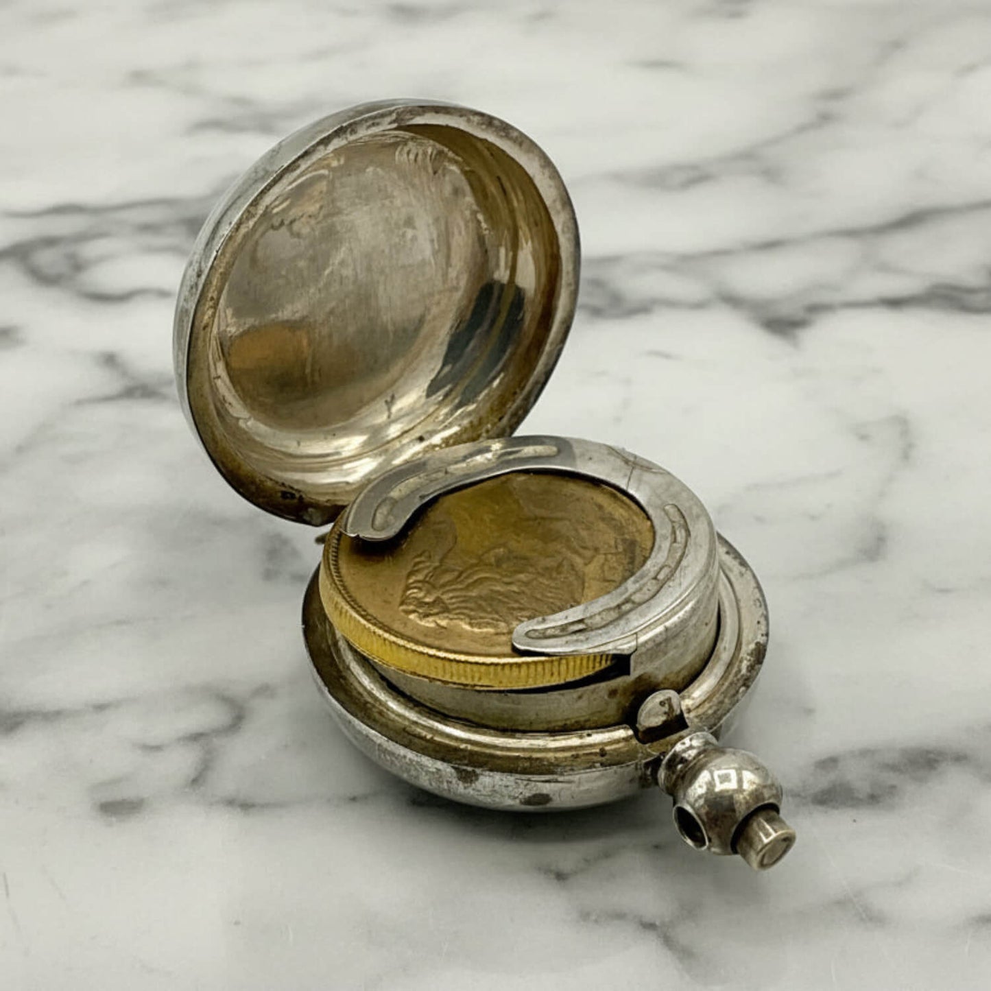 Silver coin holder with coins on a marble surface