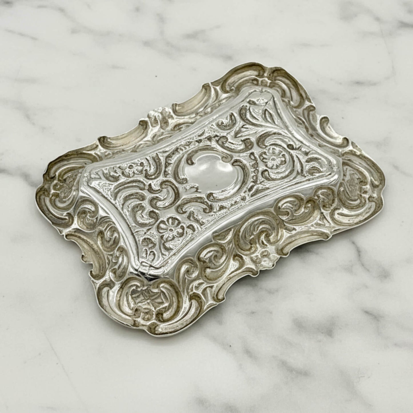 Antique Small Repousse Silver Tray upside down on a marble surface