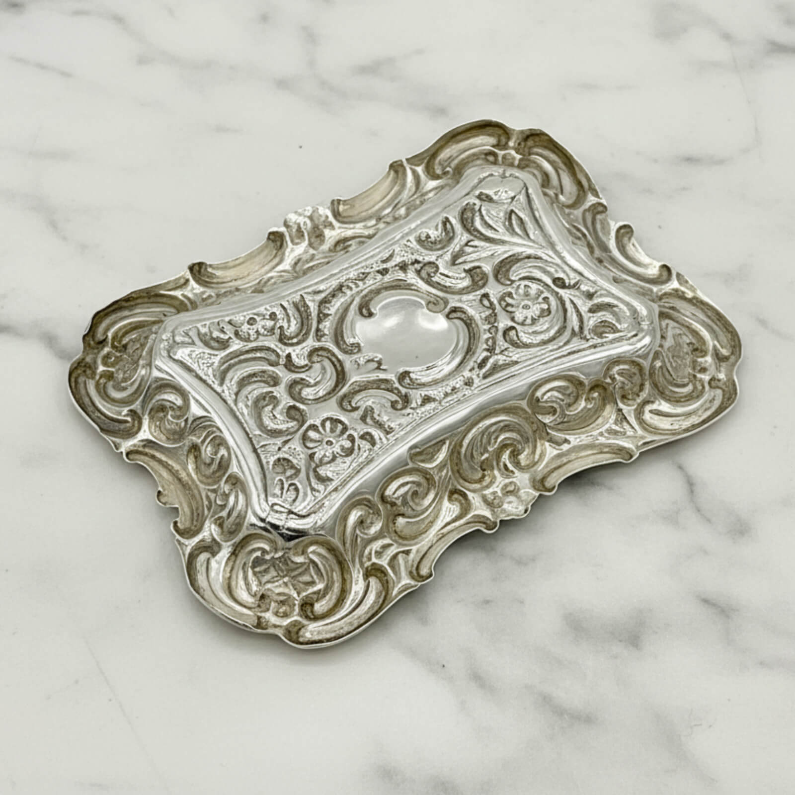 Antique Small Repousse Silver Tray upside down on a marble surface