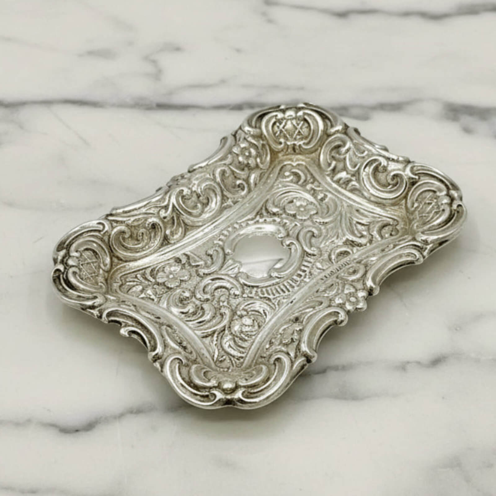 Antique Small Repousse Silver Tray on a marble surface