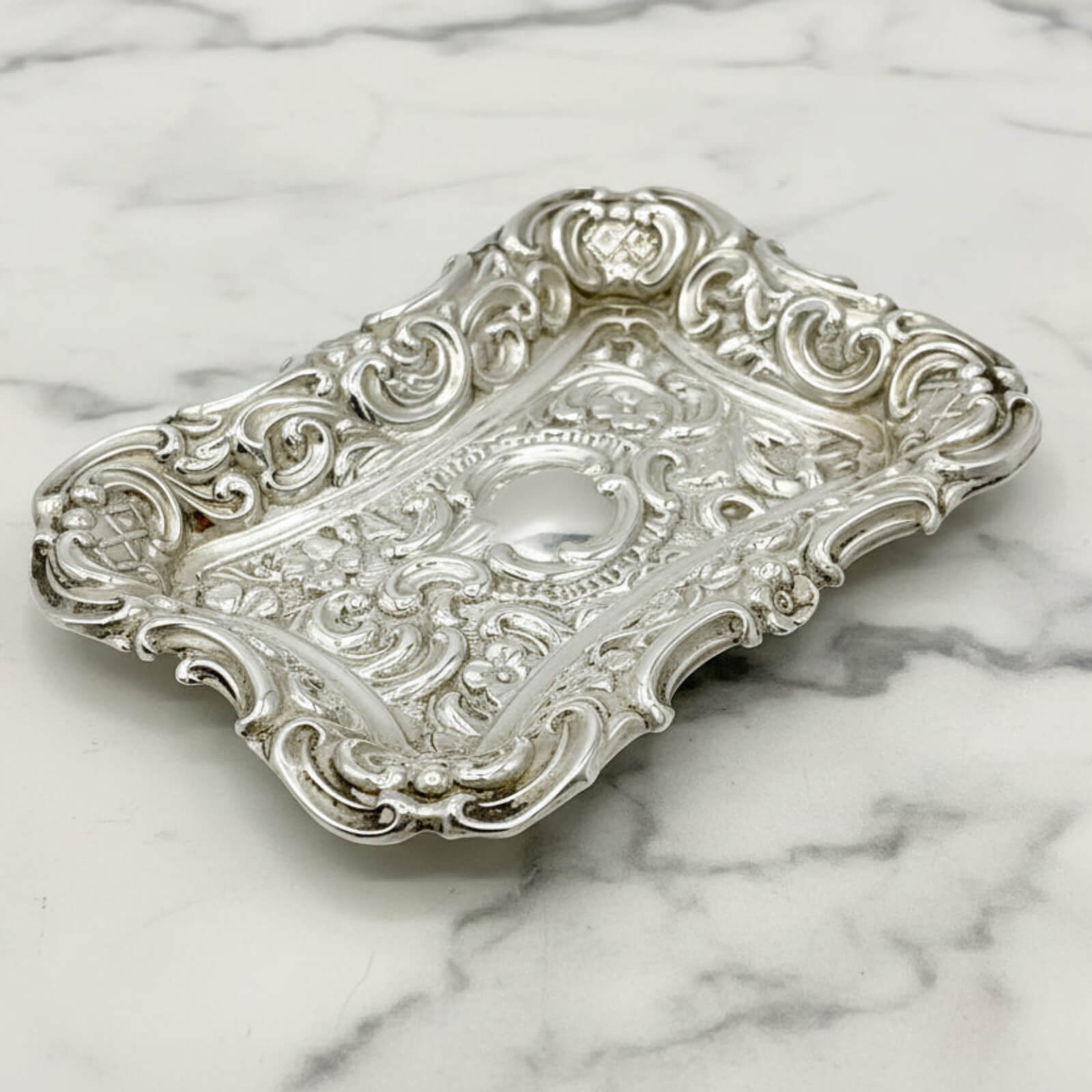 Antique Small Repousse Silver Tray on a marble surface