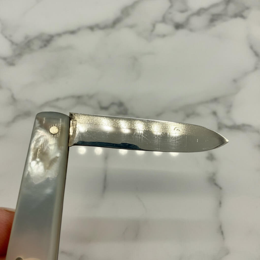 Silver pocket knife blade on a marble surface