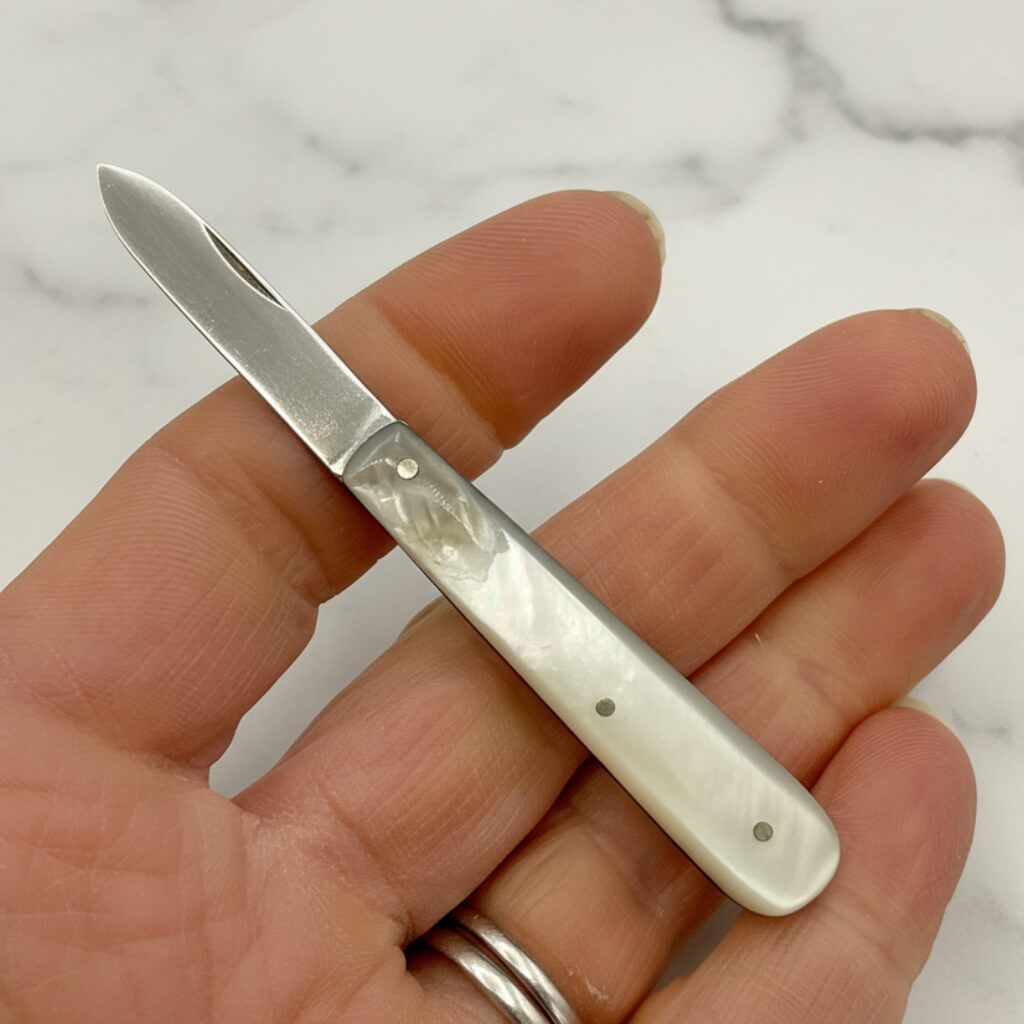 Small fruit knife held in a hand with a marble background