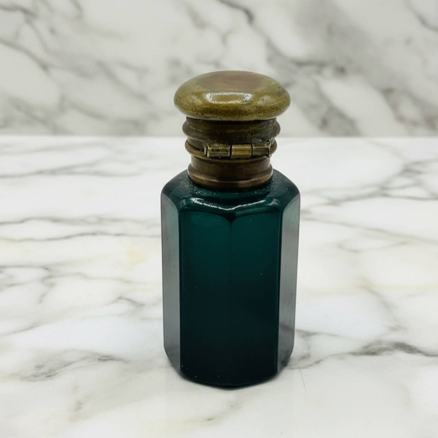 Antique blue glass bottle with a decorative cap on a marble surface