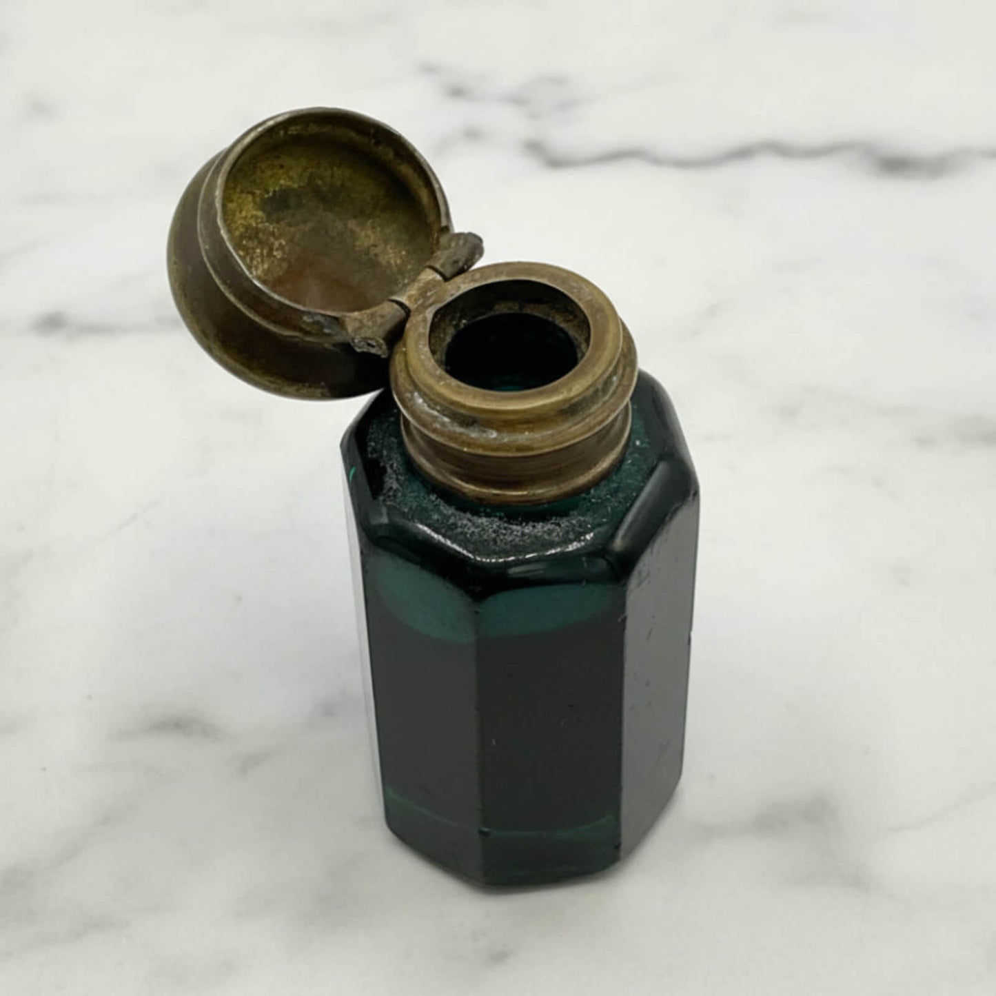antique blue glass bottle with brass cap on a marble surface