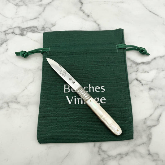 A silver fruit knife with an mother-of-pearl handle rests diagonally on a dark green drawstring pouch. The pouch features the white printed text 'Beeches Vintage'.