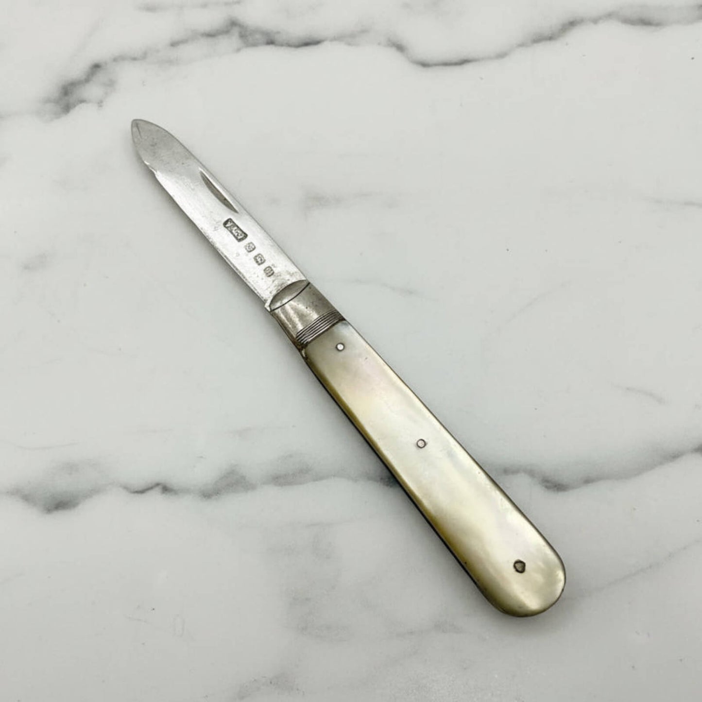 Vintage folding knife with pearl handle on a marble background